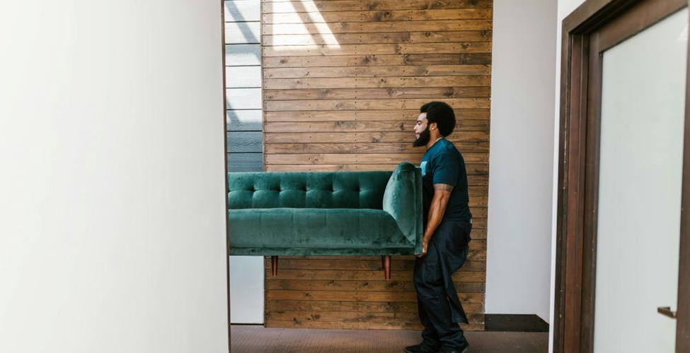 A man moving a green sofa