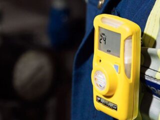 Yellow portable gas detector clipped on safety vest