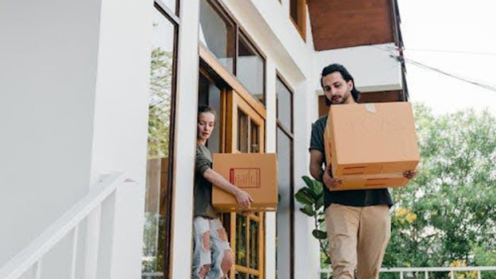 Two people carrying boxes outside
